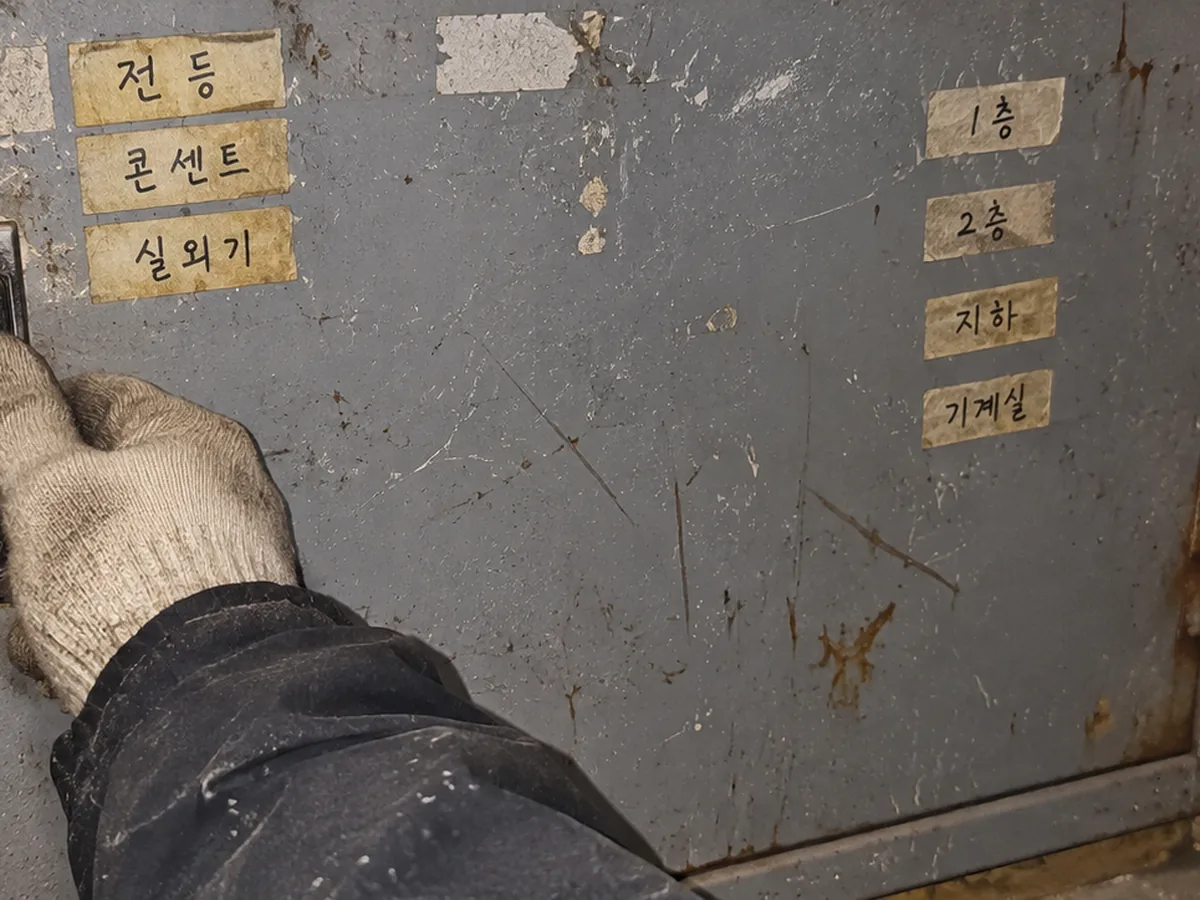 라벨이 붙은 철제 분전함 문을 여는 장갑 낀 손